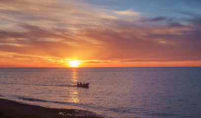 Fototapeta premium fishing boat in the sea, blue and orange sky background