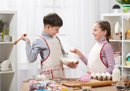 Girl and boy cooking in home kitchen. The boy breaks the egg. Healthy food concept