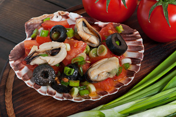 Salad of seafood mussels and vegetables tomato, decorated with green onions and olives.