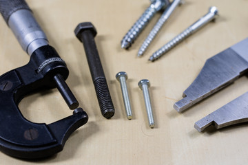 Tools and measuring accessories on a wooden workshop table. Making control measurements using calipers, micrometers and other measuring tools.