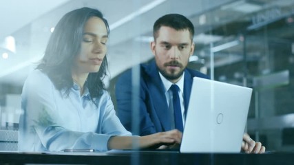 Female Accountant and Male Businessman Sitting at the Desk Having Discussion and Working on a Desktop Computer, Solving Problems. Shot on RED EPIC-W 8K Helium Cinema Camera.