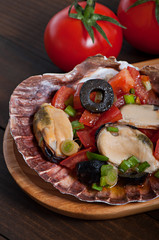 Salad of seafood mussels and vegetables tomato, decorated with green onions and olives.
