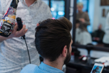 Barber shop. Man in barber's chair, hairdresser styling his hair