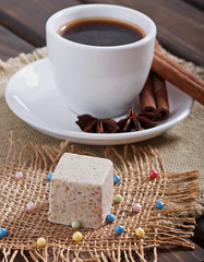 Milk sesame sweets and aromatic coffee with spices on an old wooden background.