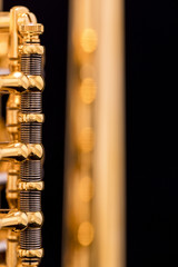 A part of a gold plated rotary trumpet on a black background