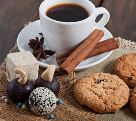 Chocolate sesame sweets and aromatic coffee with spices on an old wooden background.