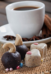 Chocolate and dairy sesame sweets in the form of heart, a cup of fragrant coffee with spices on an old wooden background.