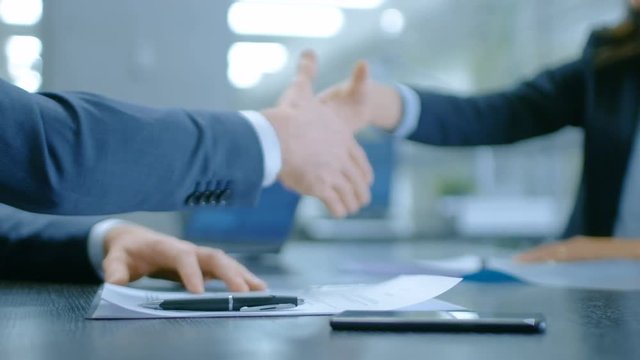 In the Office Close-up on Hands of Businesswoman and Businessman while Signing Contracts and Shaking Hands for Finishing Transaction. Stylish People in Modern Conference Room. 