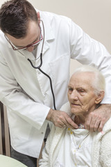 Dłonie lekarza internisty badają stetoskopem płuca bardzo starej kobiety. Lekarz internista bada...