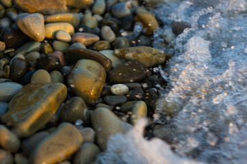 pebble stones on the sea beach, the rolling waves of the sea with foam