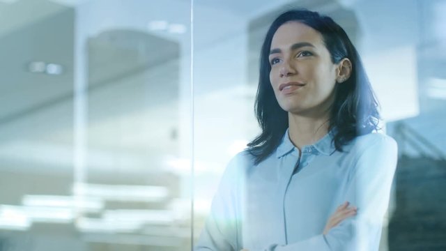 Beautiful Female CEO in Her Office Looks out of the Window on a Big City. Strong Independent Woman with Big Accomplishments Behind and Ahead of Her. Shot on RED EPIC-W 8K Helium Cinema Camera.