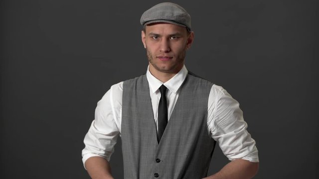 Portrait of good-looking gentleman in vintage outfit expressing disgust and aversion with face, over gray wall. Concept of emotions