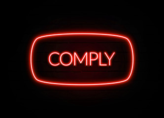 Comply neon sign on brick wall background.