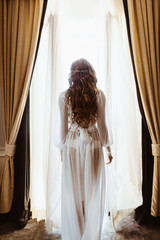 Silhouette of sexy young brunette woman in white lingerie in the doorway