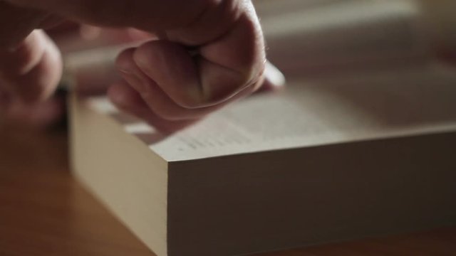 Closeup of a man's hand flipping through a paper book