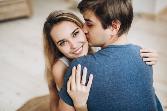Close-up photo of a lovely loving couple who embraces each other, a guy kissing a girl, and a girl looks at the camera and smiling