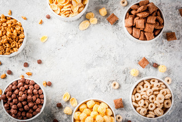 Set of various breakfast cereal corn flakes, puffs, pops, grey stone table copy space top view frame