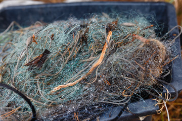 Tangled fishing net in the dew in a plastic box. Plastic box full of red white fishing net, huge floats, nylon rope used in fishing industry