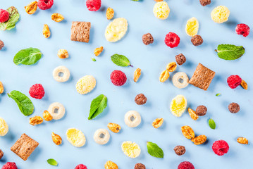 Healthy breakfast ingredients concept. Various breakfast cereal, raspberries and mint on blue background, copy space top view