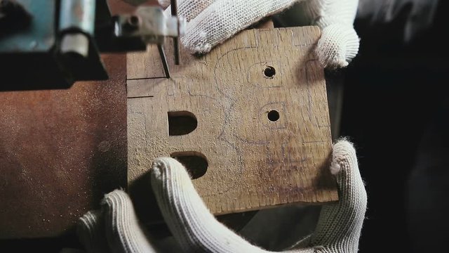 hands in white gloves jigsaw to cut a wooden workpiece, the symbol of bitcoin