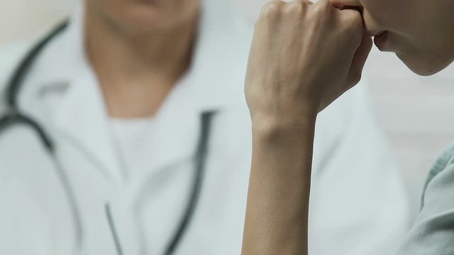 Experienced physician informing Asian woman about incurable disease, bad news