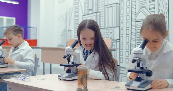Teen at school laboratory studying biology, looking through microscope