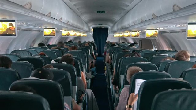 Passengers are sitting and sleeping on an airplane.