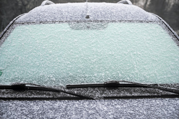 frozen windshield of a car with ice and snow, concept of traffic risks in winter, copy space