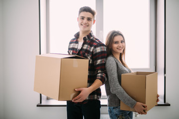 Couple with boxes moving into new home smiling. young couple on moving day.