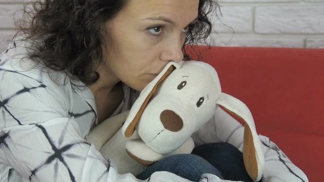 A sad woman hugs a child's toy.