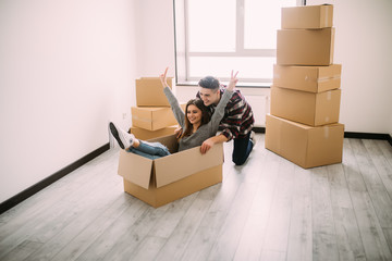 Fototapeta premium The young woman sitting in a cardboard box. Moving, purchase of new habitation.