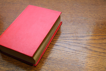 Red book on a wooden background, space for text, concept reading