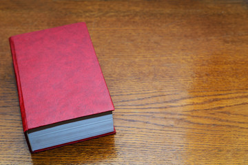 Red book on a wooden background, space for text, concept reading