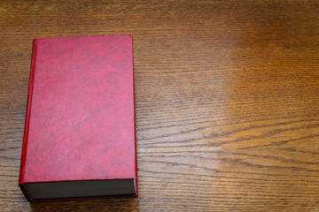 Red book on a wooden background, space for text, concept reading