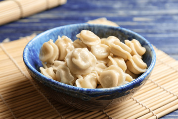 Bowl with tasty dumplings on bamboo mat
