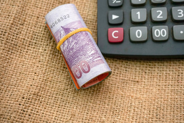 Banknotes or money tied with rubber band , black calculator isolated on textured sack background.