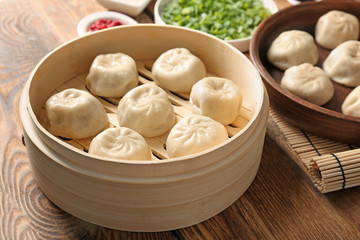 Bamboo steamer with tasty baozi dumplings on table