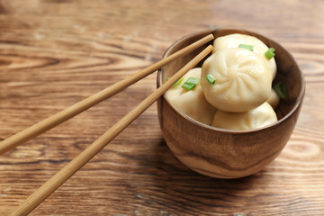 Bowl with tasty baozi dumplings on wooden background
