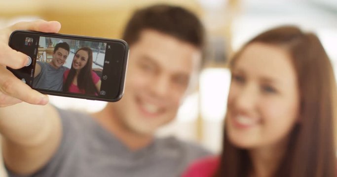 4K Attractive young couple relaxing at home pose to take a selfie with smartphone. Slow motion