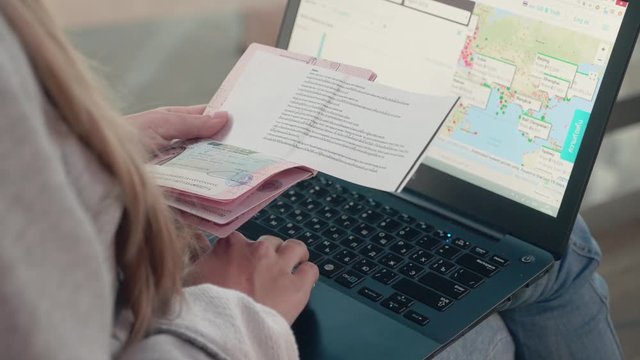 Booking tickets online. Hands of a woman with a passport and laptop.