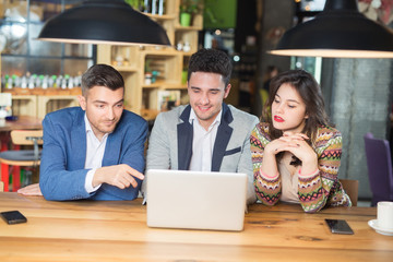 Three Businesspeople Working At Laptop In cafe