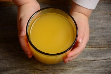 The glass of fresh orange juice in the baby hand 