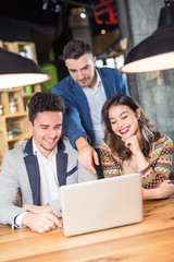 Three Businesspeople Working At Laptop In cafe