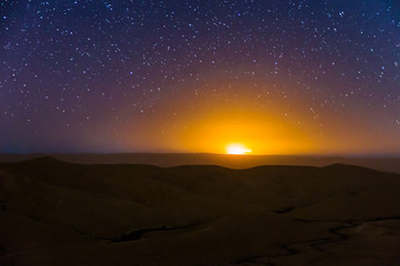 Night sky stars over desert hills sunset light.