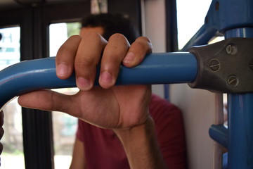 Mão segurando barra de trasporte público