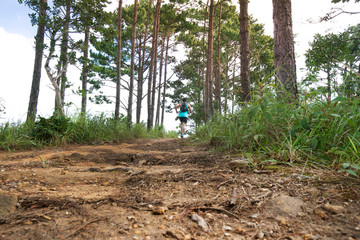 Athletic runner running on tropical forest trail, dramatic tone