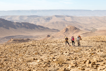 Three backpackers standing mountains trail , Negev desert,  Israel.