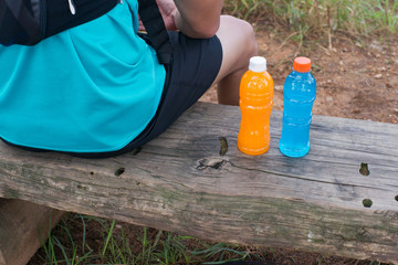 Trail runner sitting with bottle of energy drink and orange juice.
