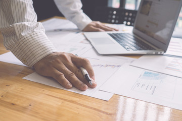 Business plan and strategy concept, businessman hand working on new modern computer ,analyzing income charts and graphs with laptop,business documents on office table on background