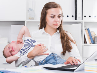 Woman is working on laptop while child naughty